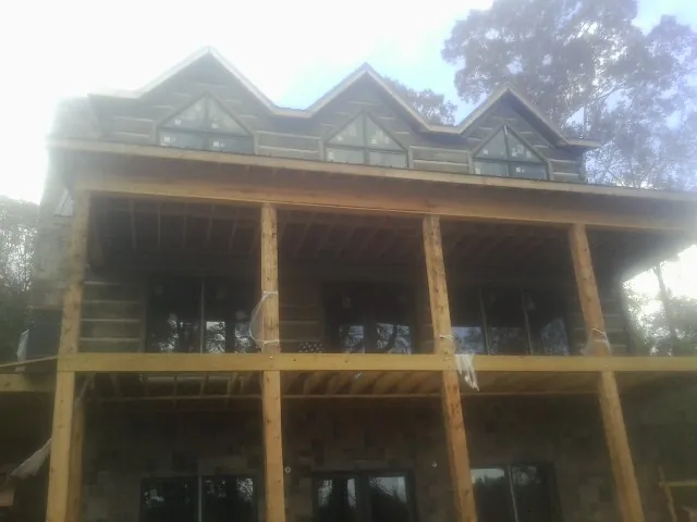 Dormers and porch framing on a large log home under construction — Roof Coating work by our crew in Westphalia