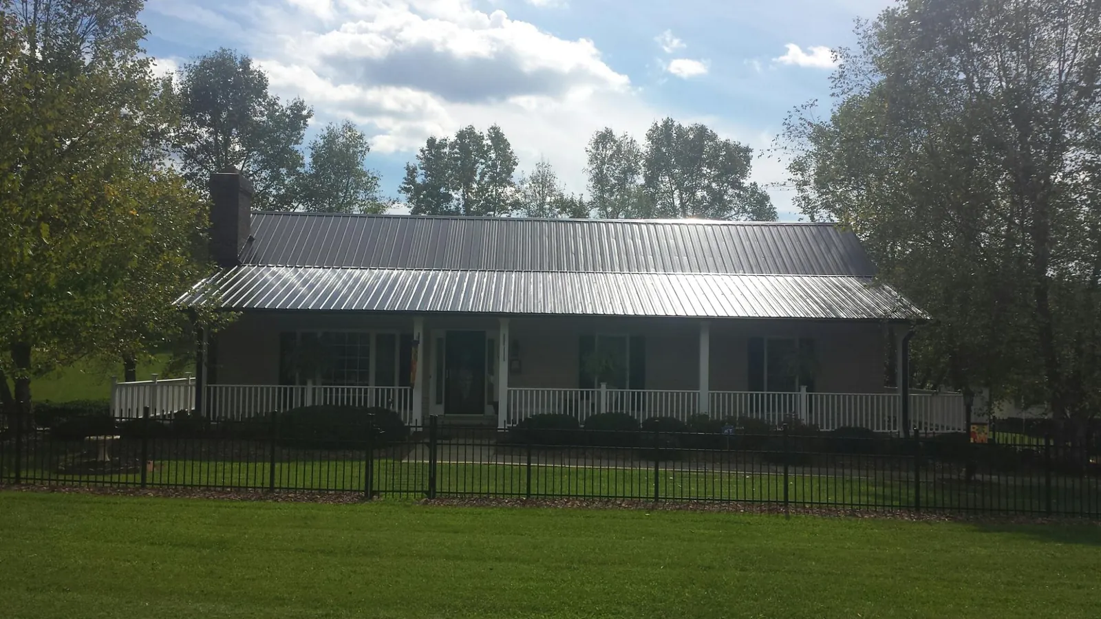 Gray metal roof on a brick ranch with a full width front porch — Gutter Guard Installation work by our crew in Westphalia