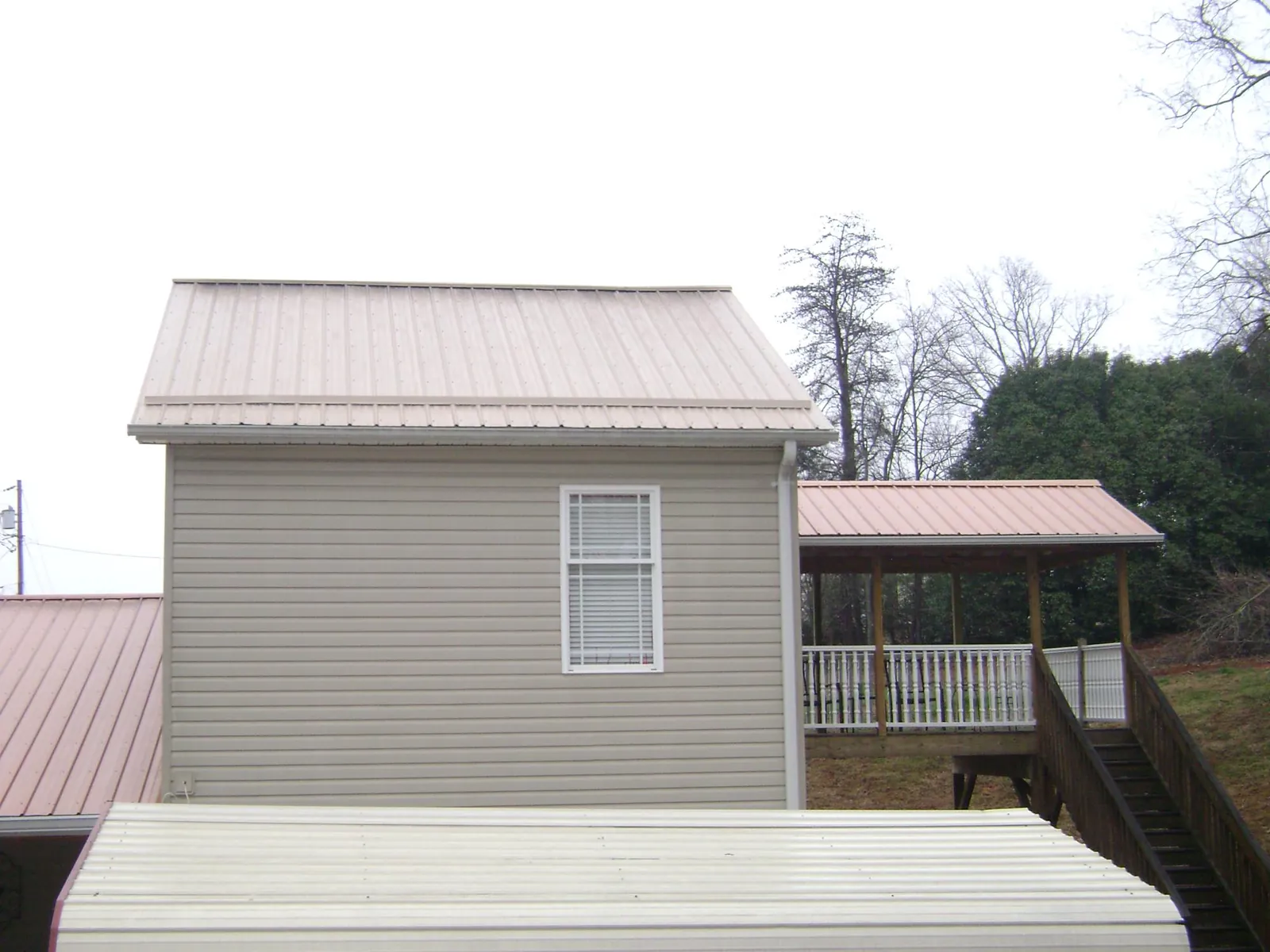 Tan metal roofs on a two story addition and attached porch, from a Roof Replacement job in Westphalia