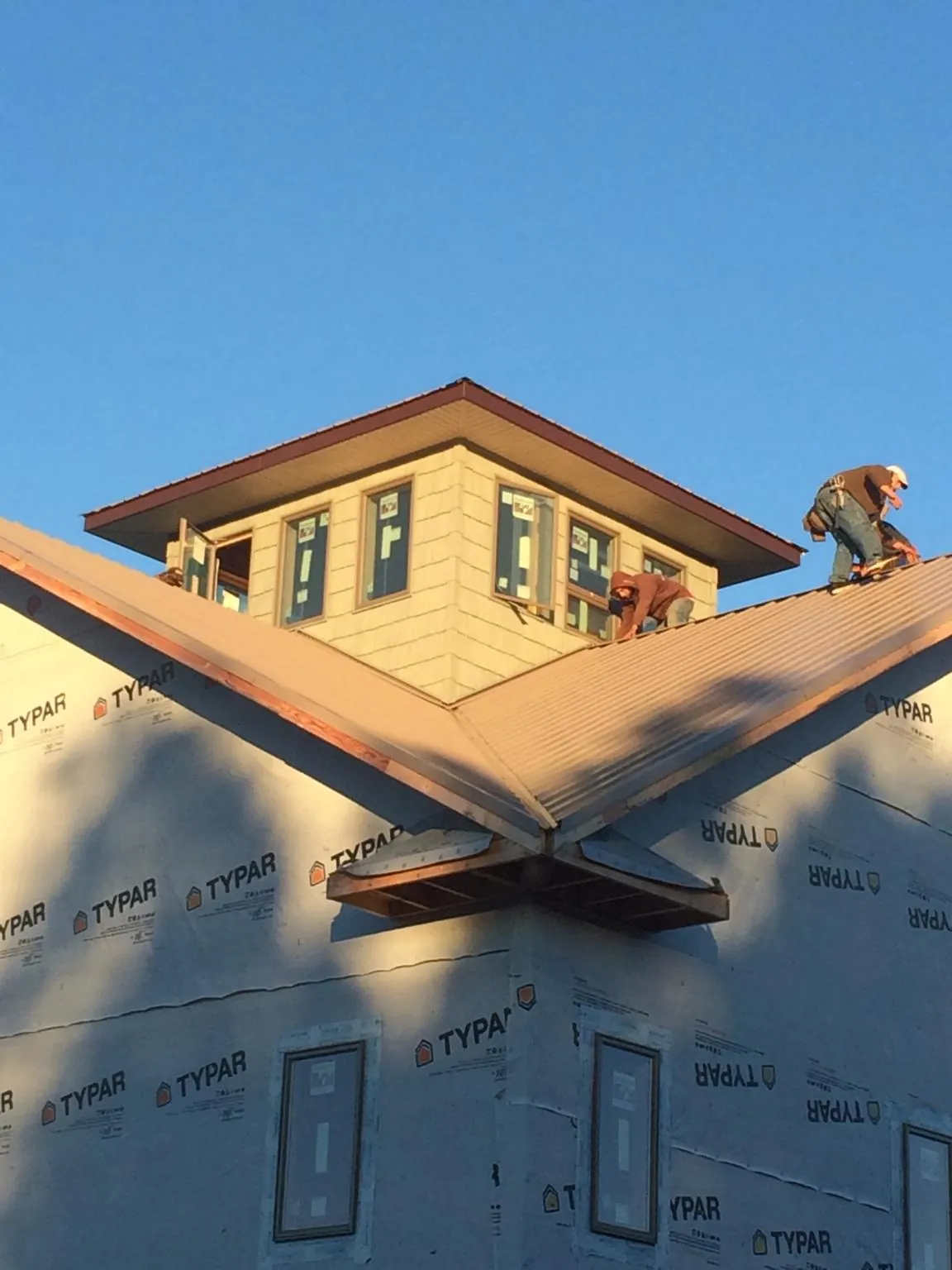 Roofers working around a rooftop cupola on a new metal roof at sunset — Roof Waterproofing in Westphalia by Roofing Brothers